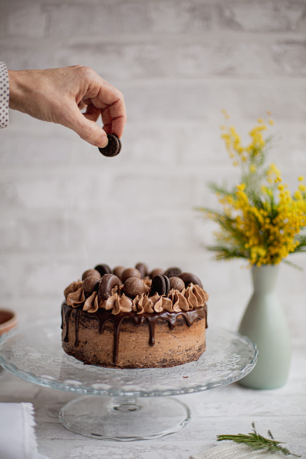 a hand holding a knife over a chocolate cake