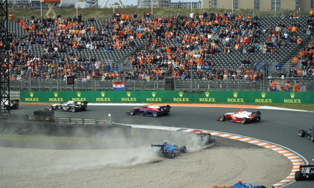 a group of race cars on a track with a crowd watching