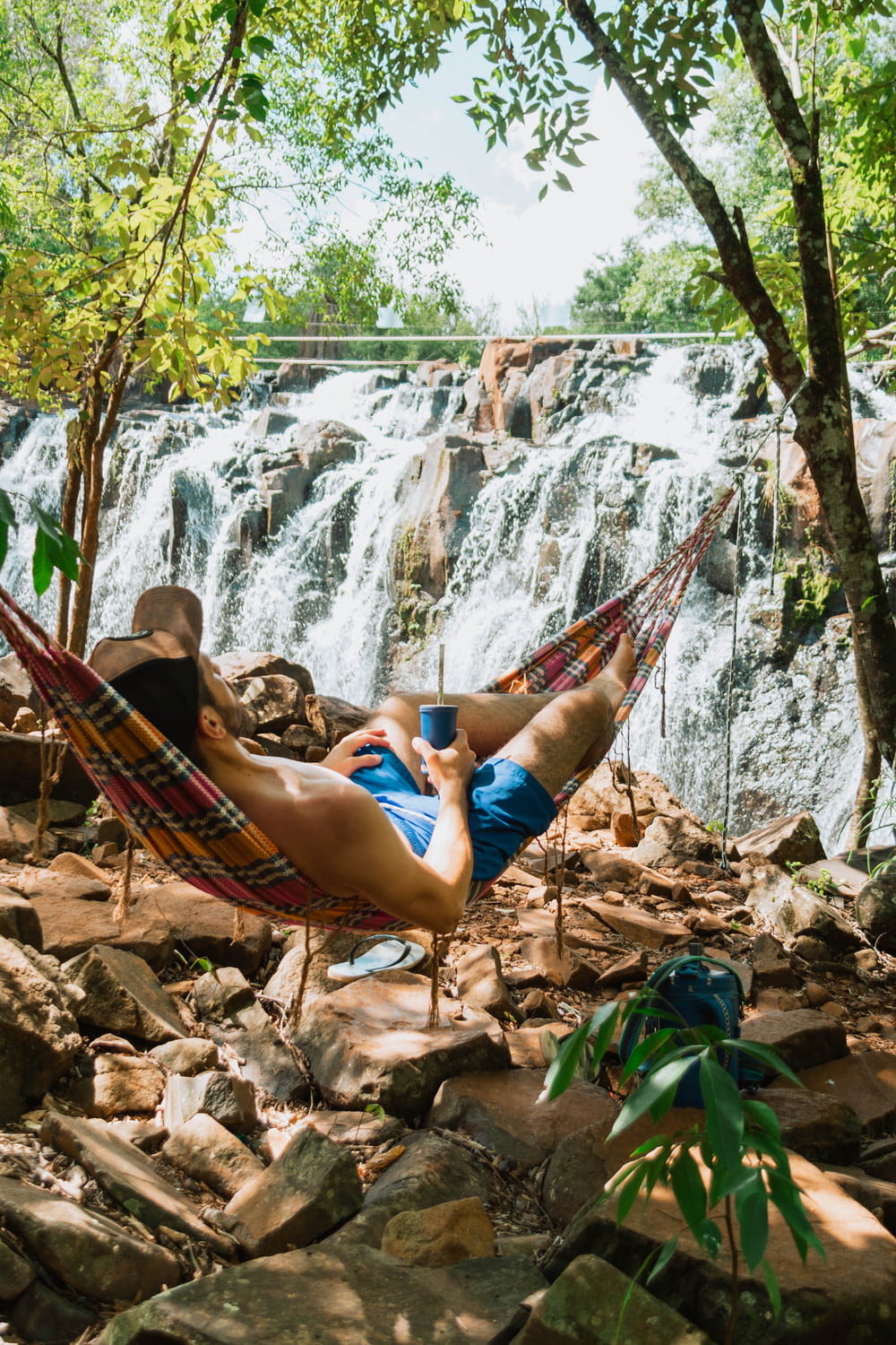 a person lying on a hammock in front of a waterfall