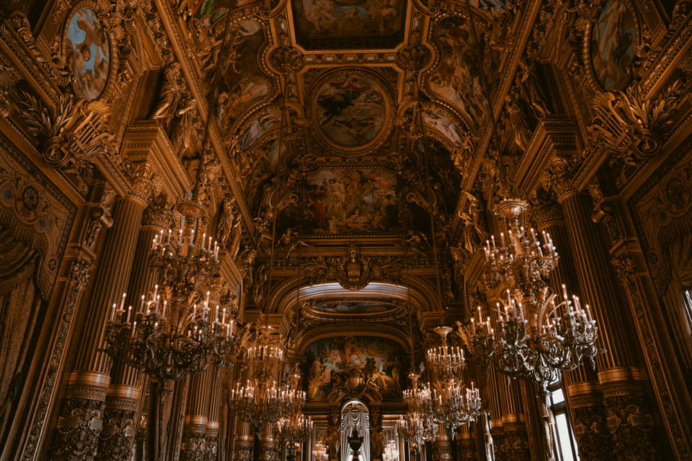 a large ornate room with chandeliers and statues with Palais Garnier in the background
