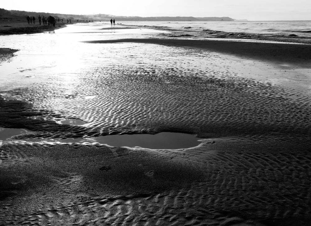a black and white photo of a beach with a body of water