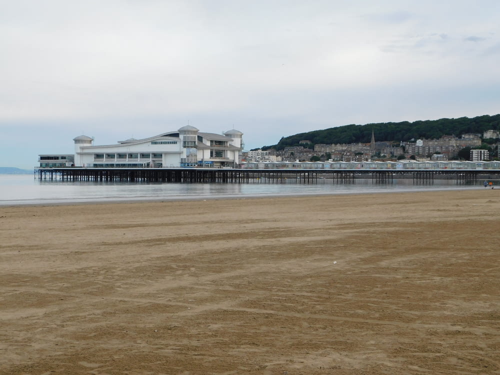 a beach with a pier and buildings in the background