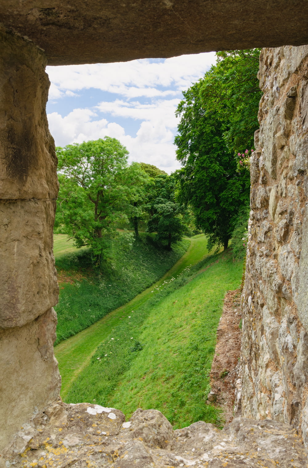 a view of a green field through a stone wall