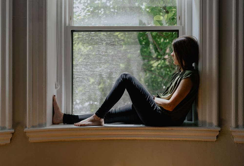 a woman sitting on a window sill