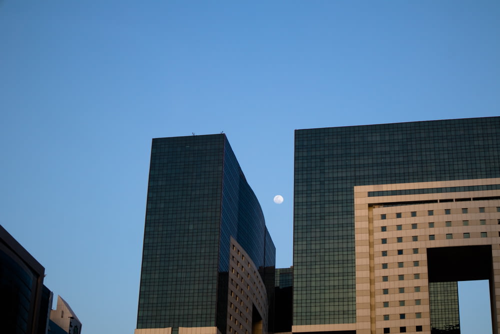 a moon in the sky above a group of tall buildings