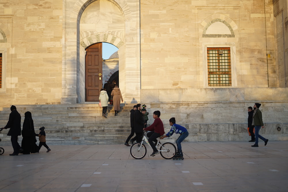 a group of people walking and riding bikes on a sidewalk