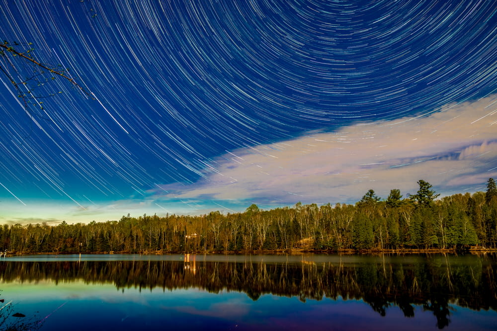 a lake with trees and a starry sky above