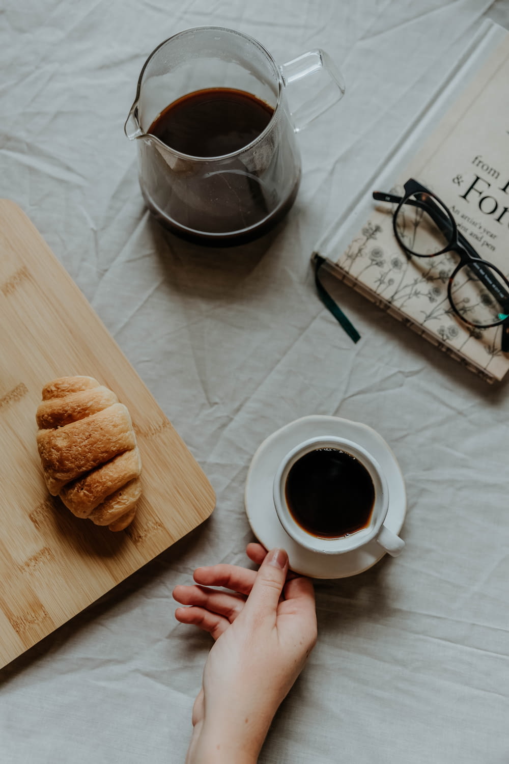 a hand holding a cup of coffee next to a tray of pastries