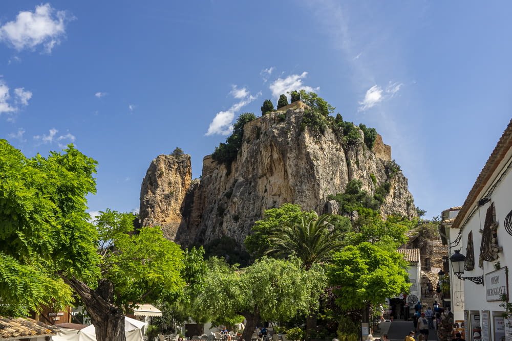 a large rock formation with trees and people below