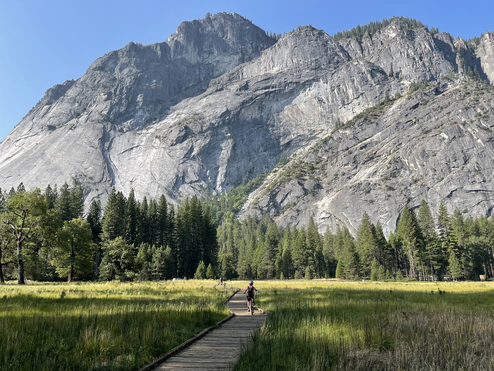 a person walking on a path in front of a mountain
