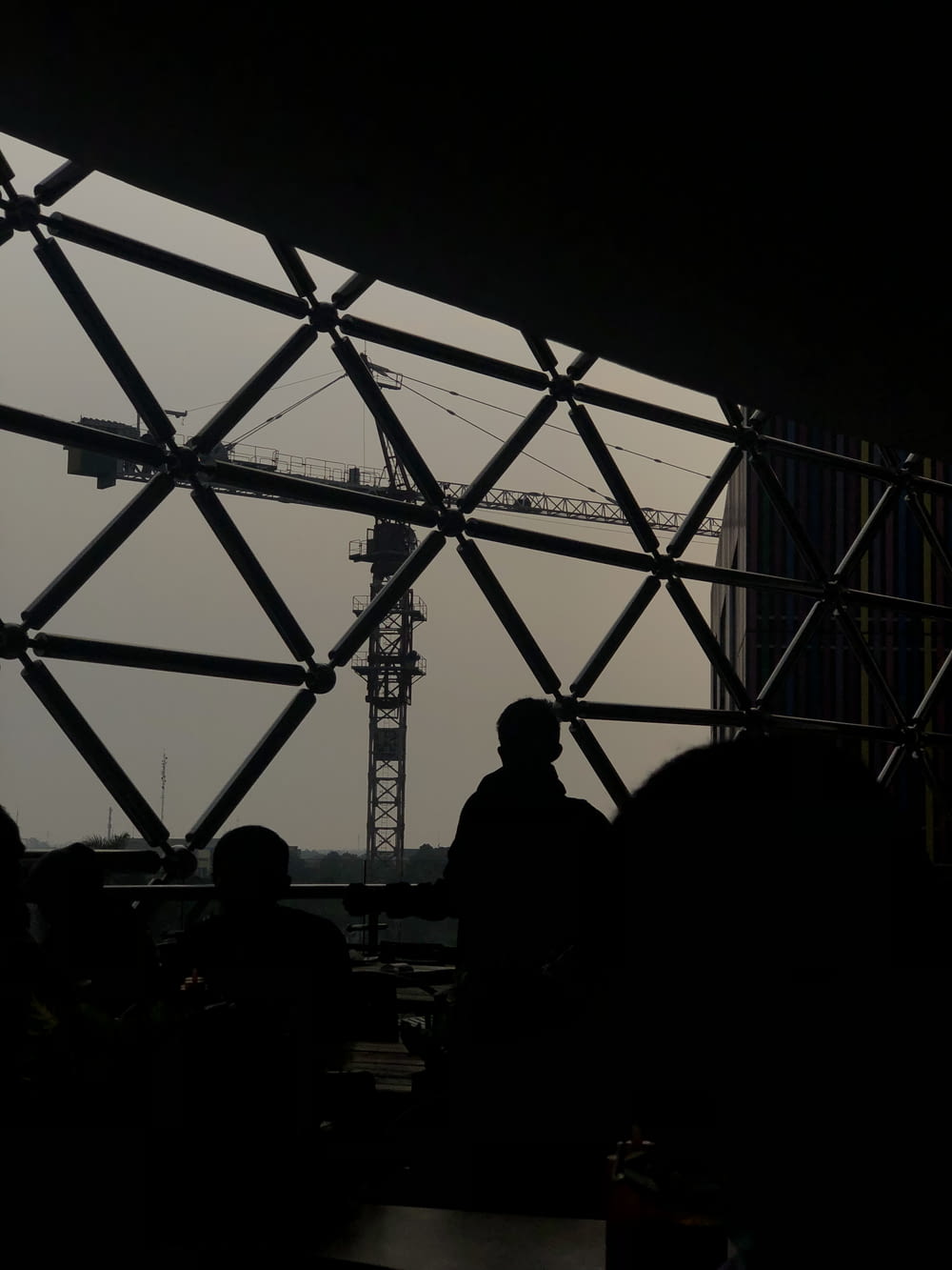 a group of people sitting under a large metal structure