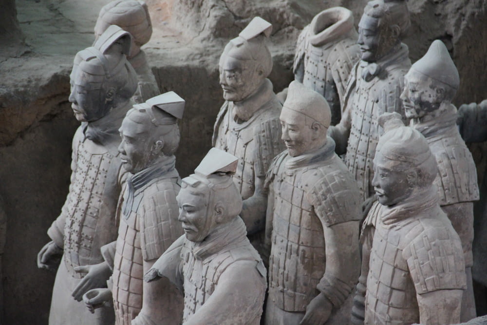 a group of people wearing white hats with Terracotta Army in the background