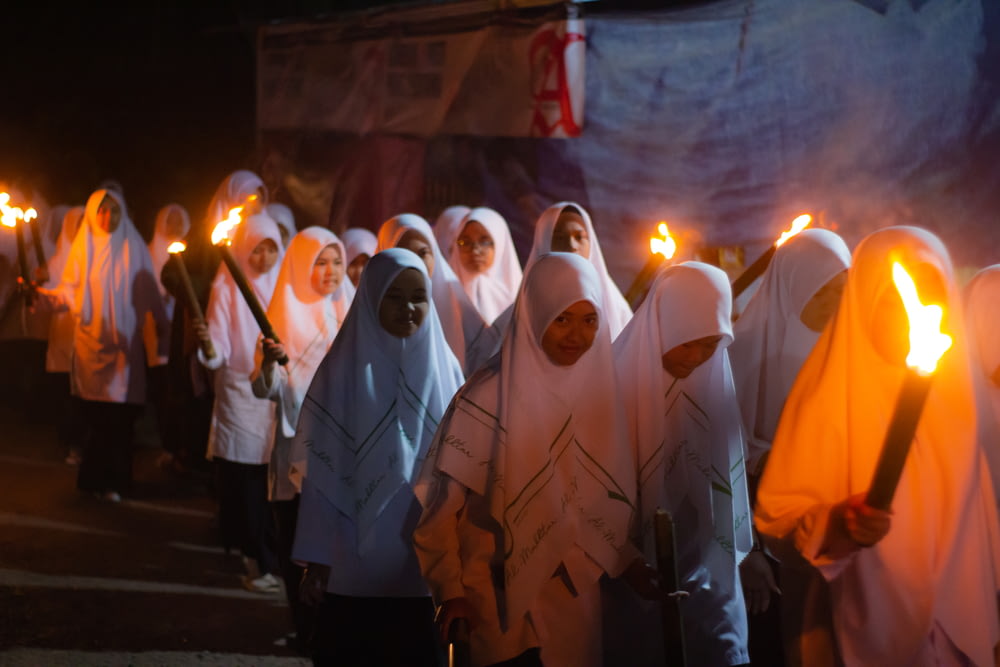 a group of people wearing white robes and holding candles