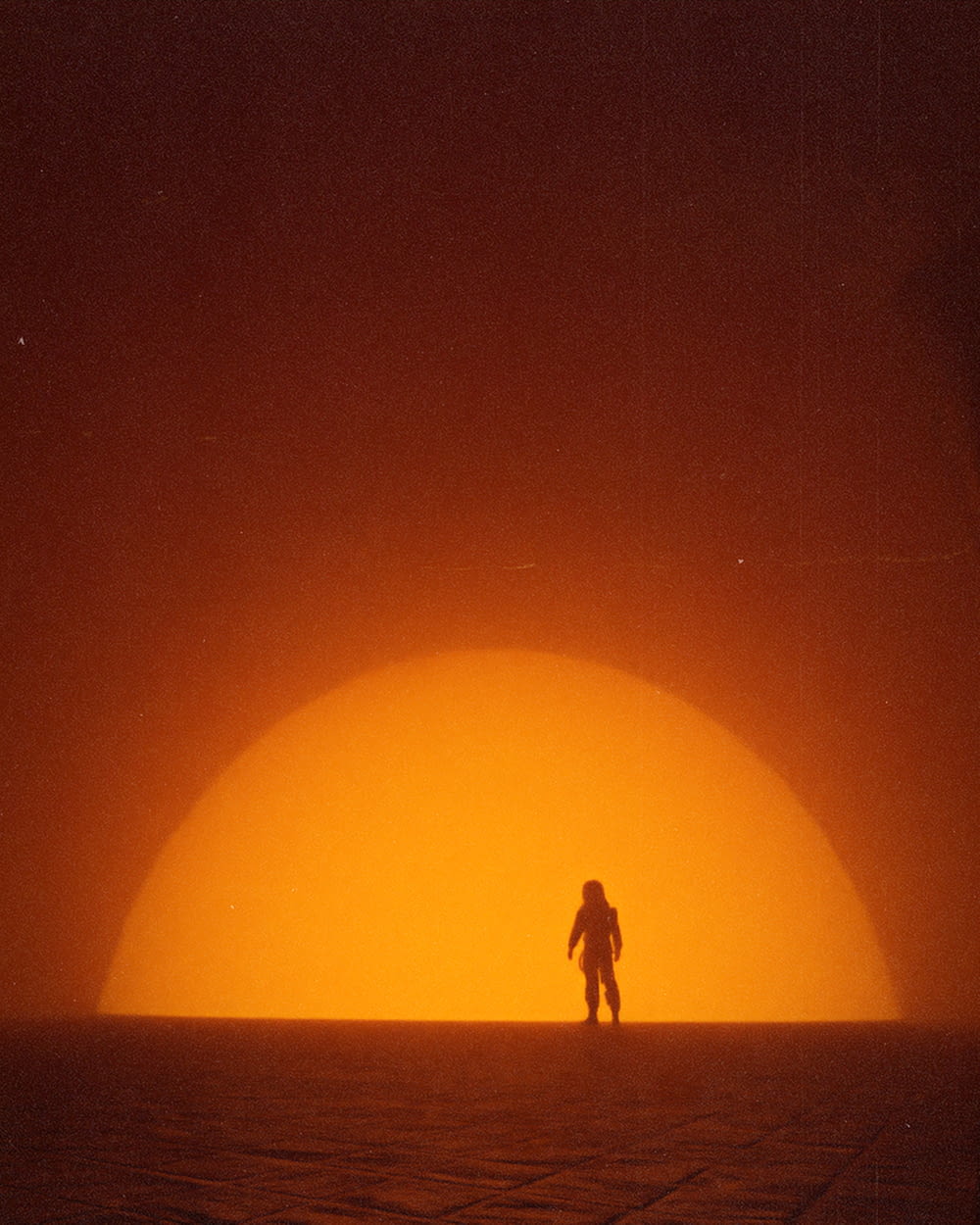 a person standing in front of a large orange moon