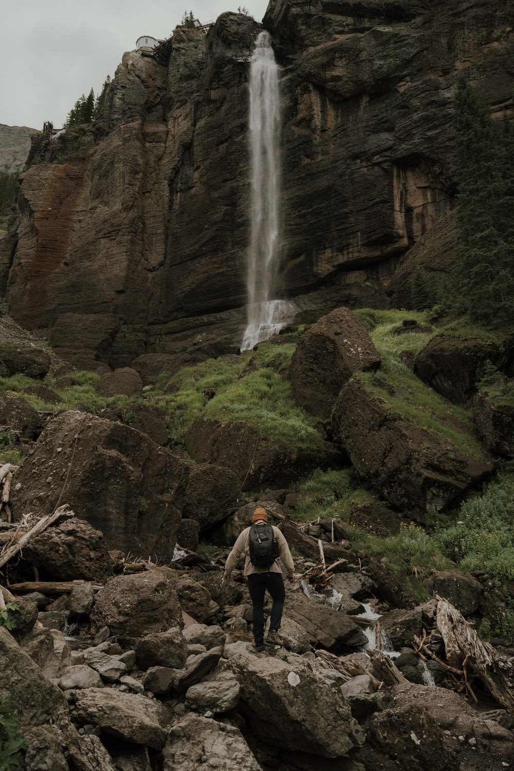 a person standing on a rocky hillside with a waterfall in the background