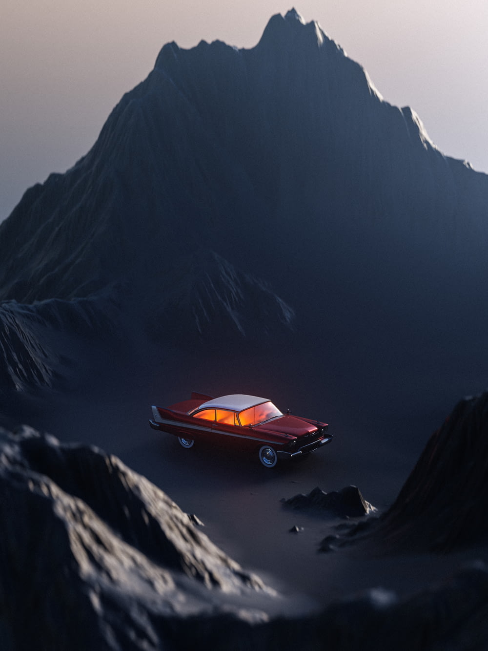 a red car parked on a rocky surface with mountains in the background