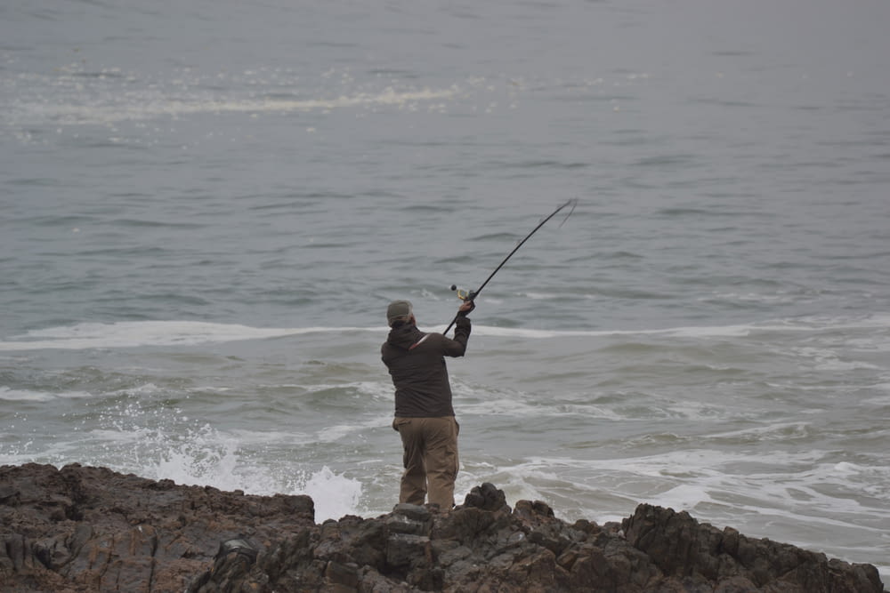 a man fishing on a rocky shore