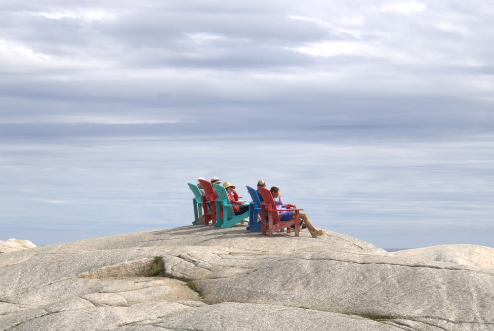 a group of people sitting on a bench on a rocky beach
