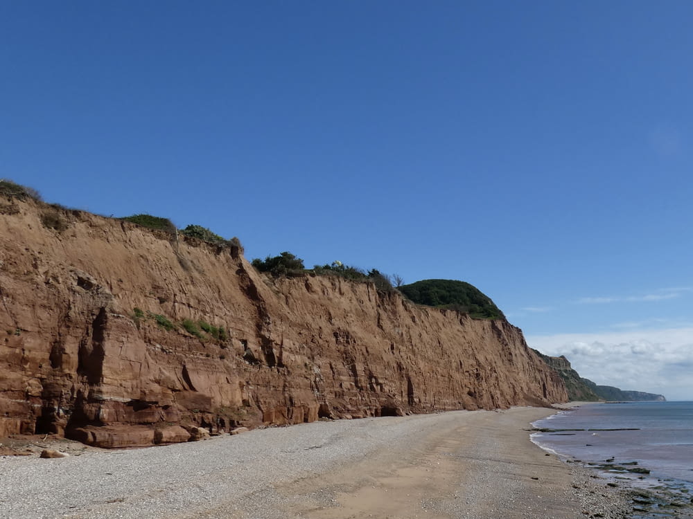 a rocky cliff next to a beach with Calvert Cliffs State Park in the background