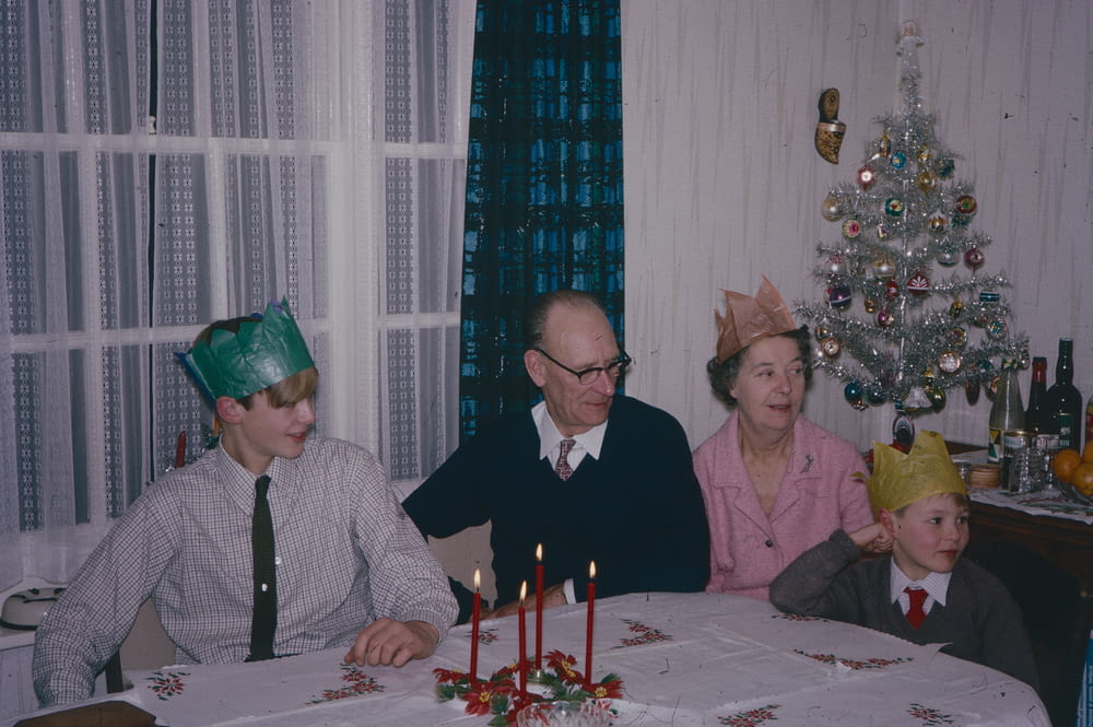 a group of people sitting around a table with a christmas tree
