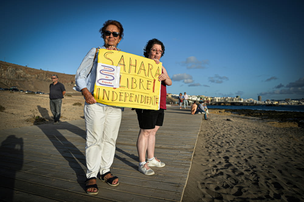 a man and woman holding a sign on a beach