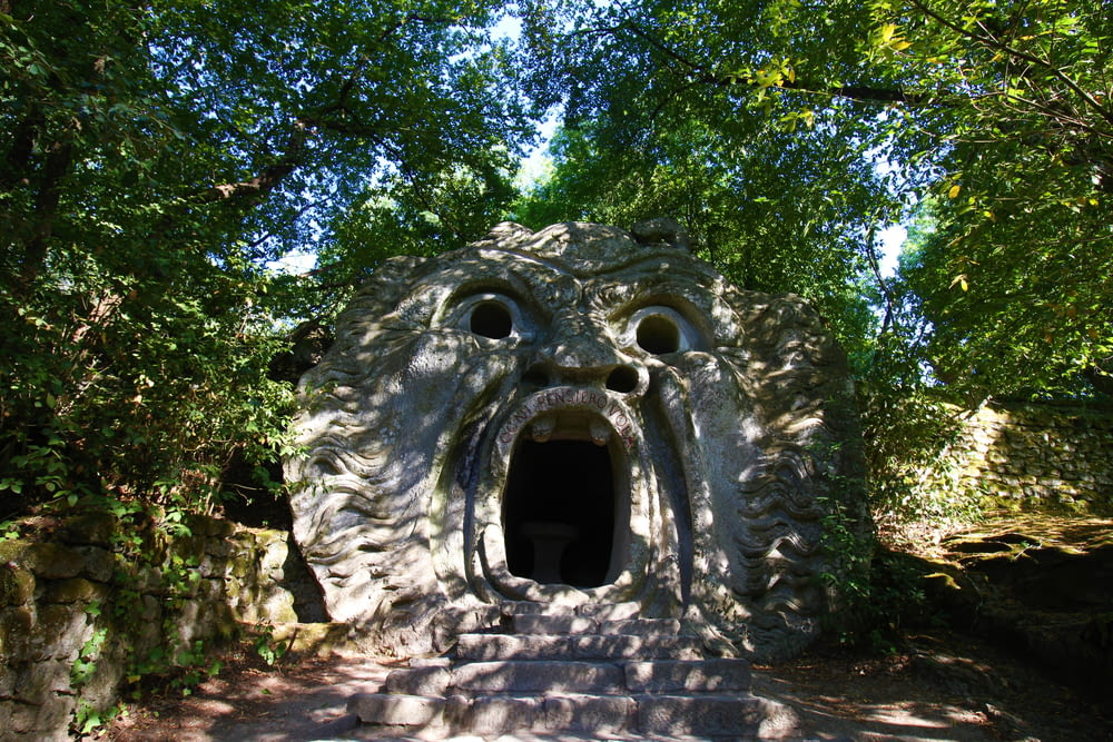 a stone structure with a hole in it surrounded by trees
