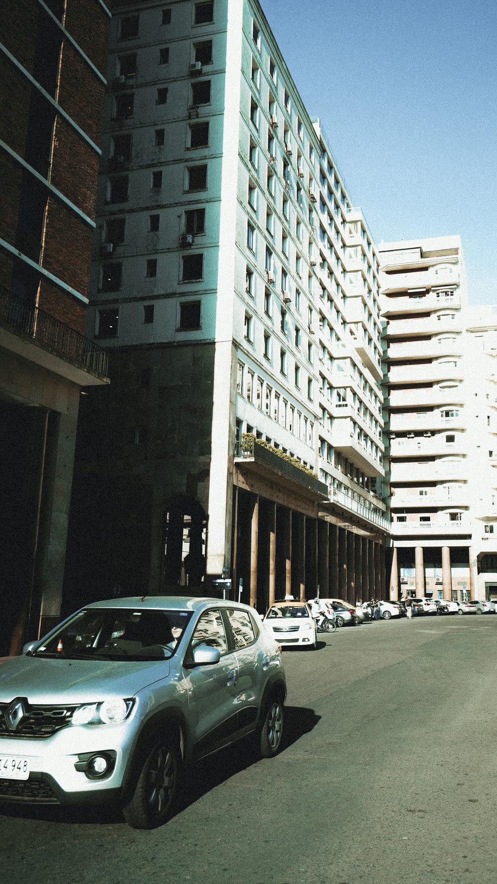 cars parked on the side of a road next to a tall building