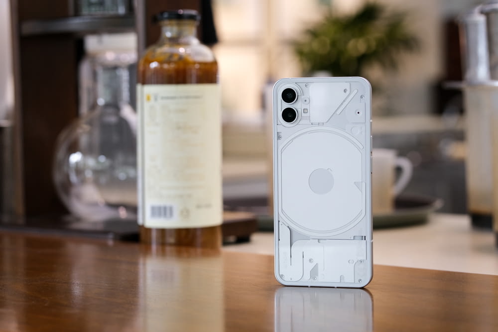 a white cell phone with a bottle of alcohol in the background