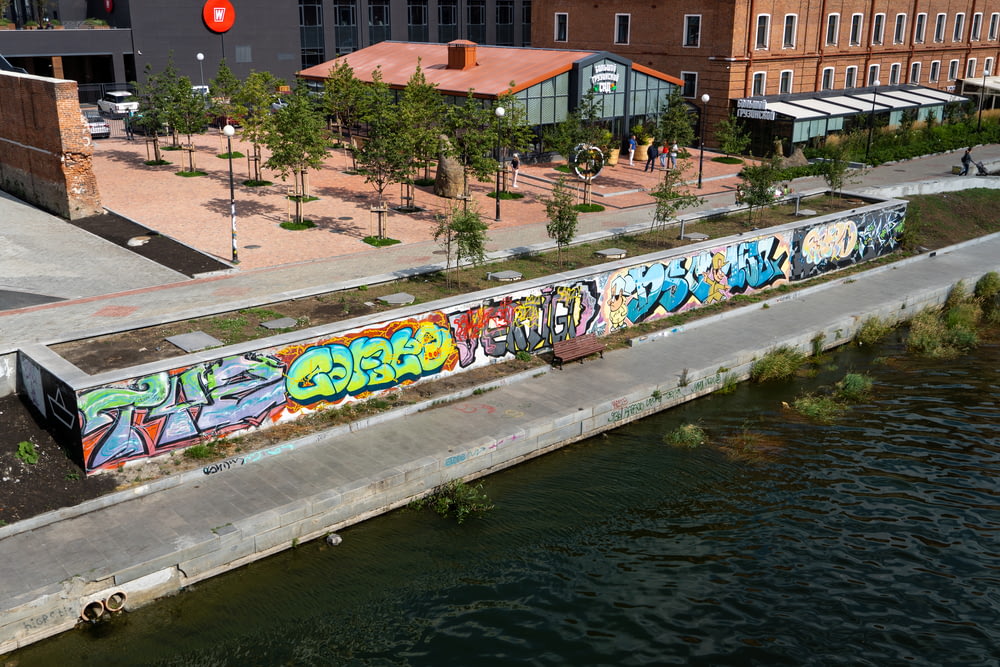 a body of water with a wall with graffiti on it