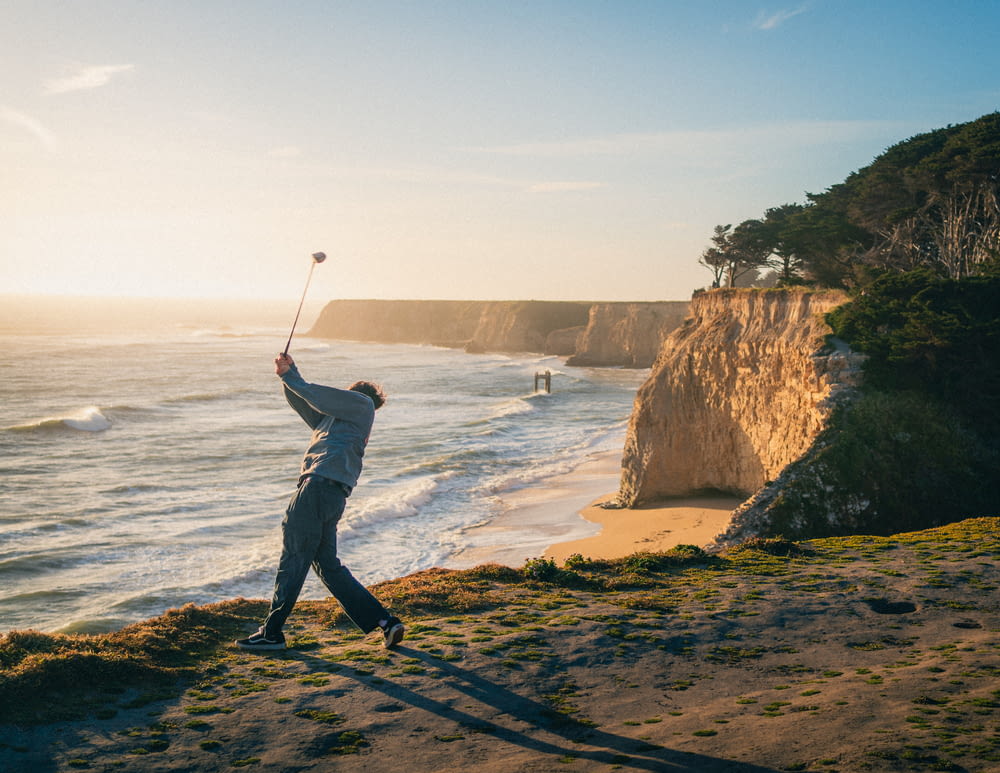 a man playing golf on a beach