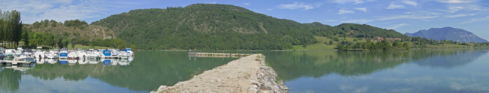 a body of water with boats on it and hills in the back