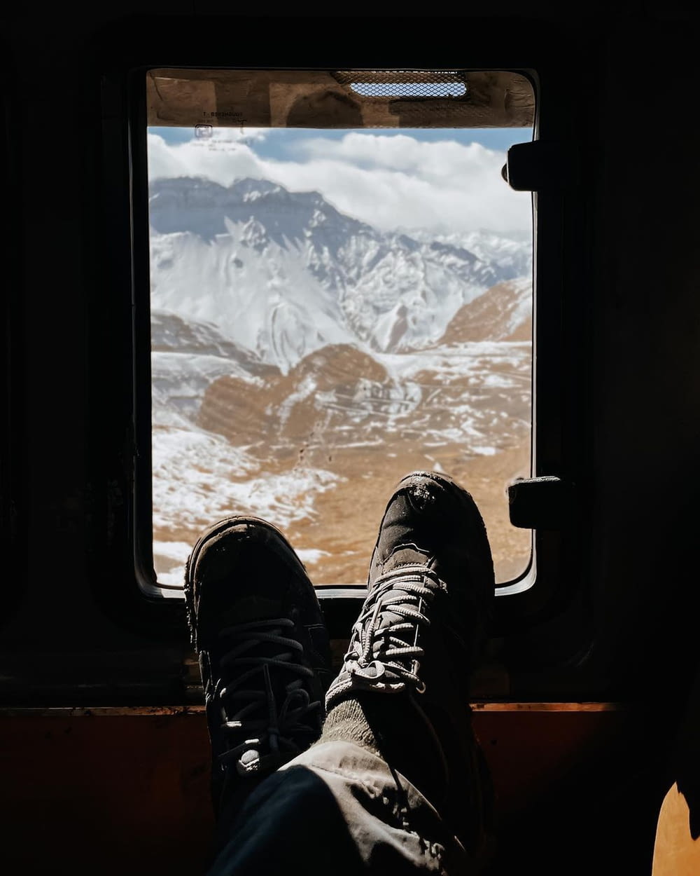 a person's feet on a window sill looking out at a snowy mountain range