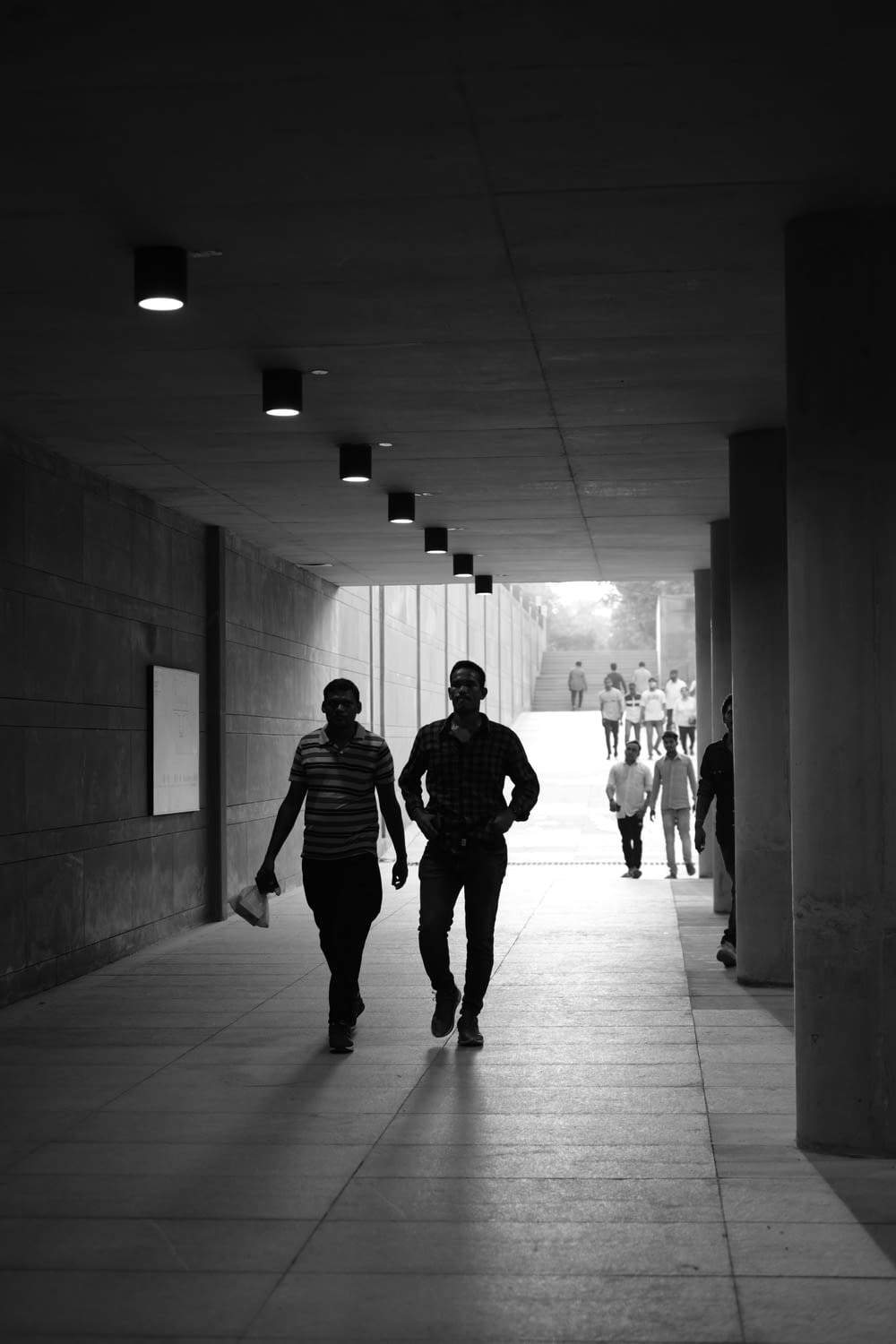 a man and woman walking down a hall with people walking