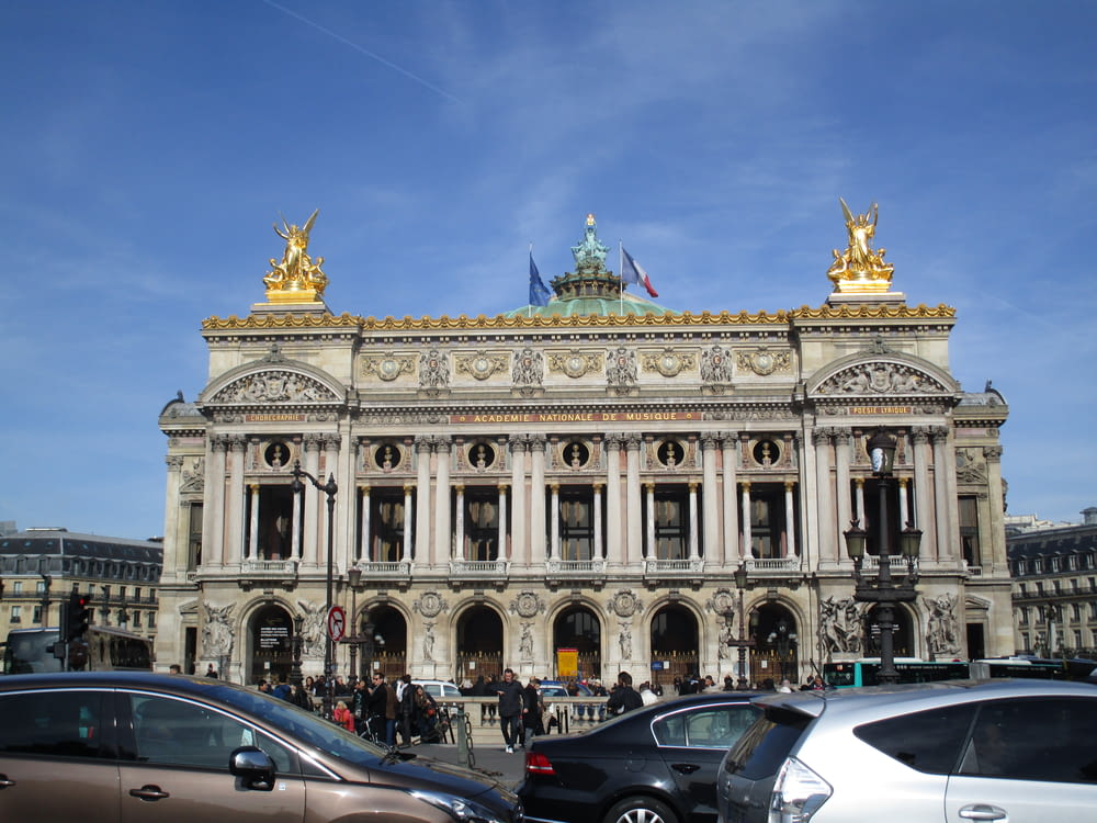 a large building with statues on top with Palais Garnier in the background