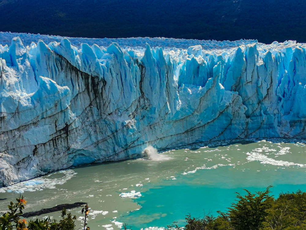 a large glacier with water below with Perito Moreno Glacier in the background
