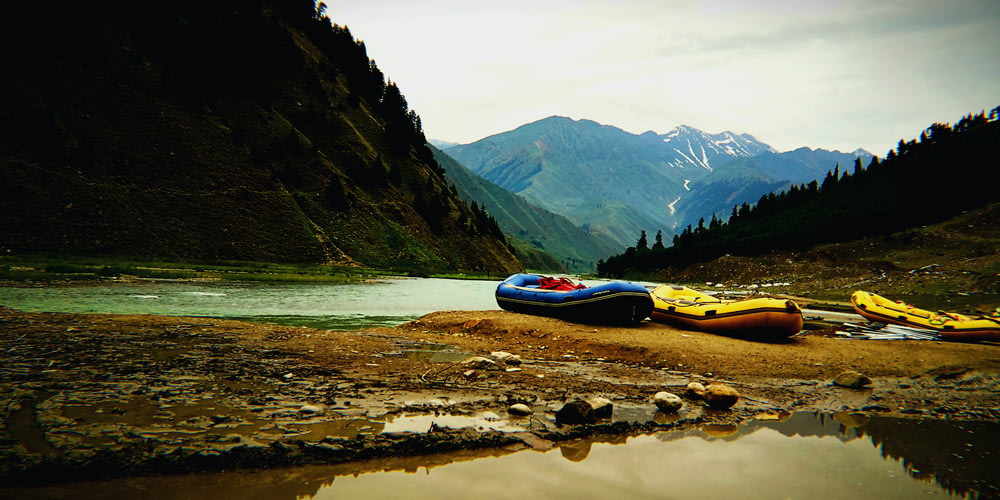 a group of kayaks on a rocky shore by a lake