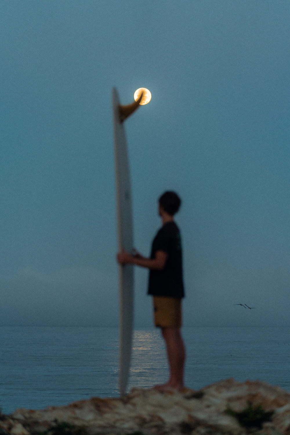 a man standing next to a light post on a beach