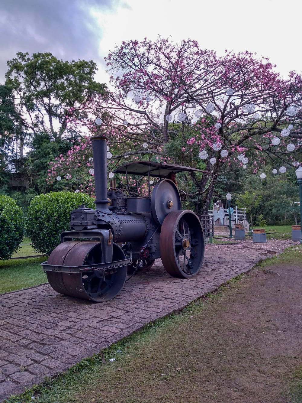 a cannon on a brick path with trees and flowers in the background