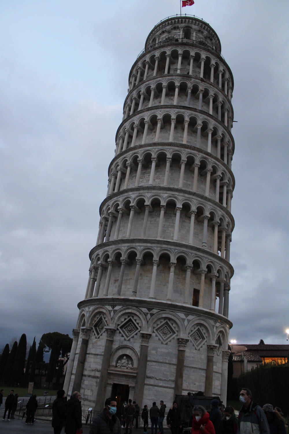 ein großer Turm mit Menschen um ihn herum mit dem Schiefen Turm von Pisa im Hintergrund