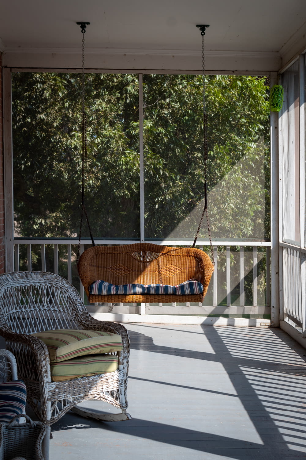 a deck with a hammock and a chair and a window with trees in the background