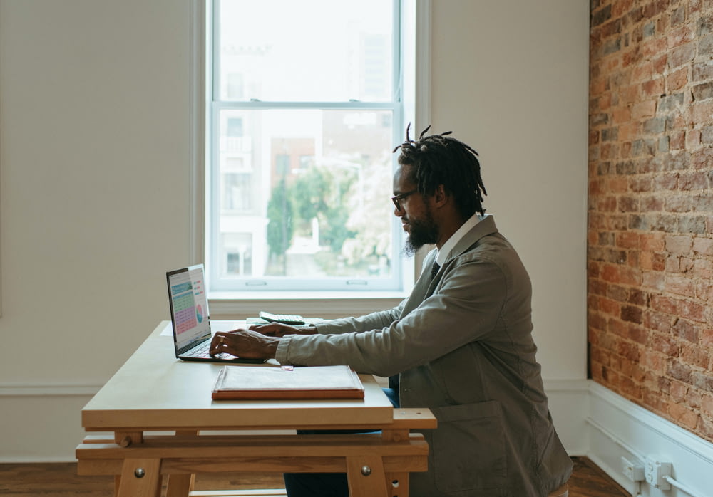 une personne assise à un bureau avec un ordinateur portable et des papiers