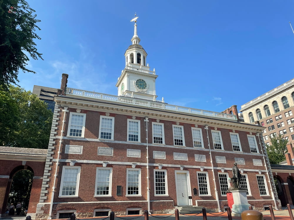 a large brick building with a clock tower with Independence Hall in the background