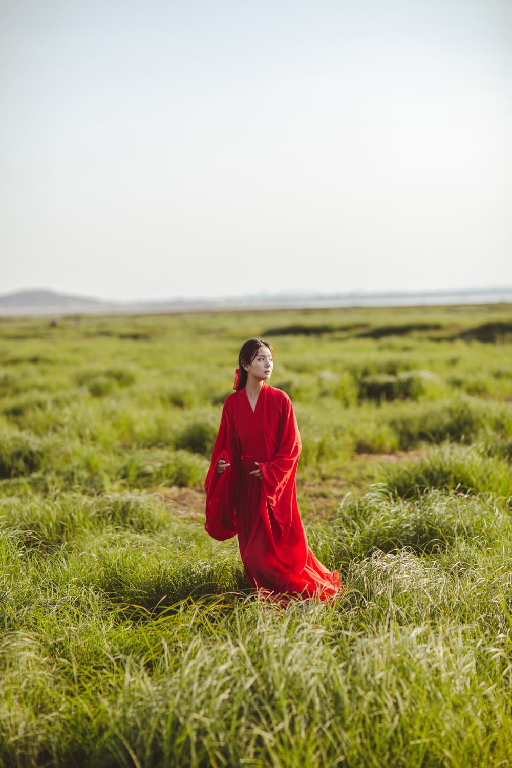 a man in a red dress standing in a field of grass