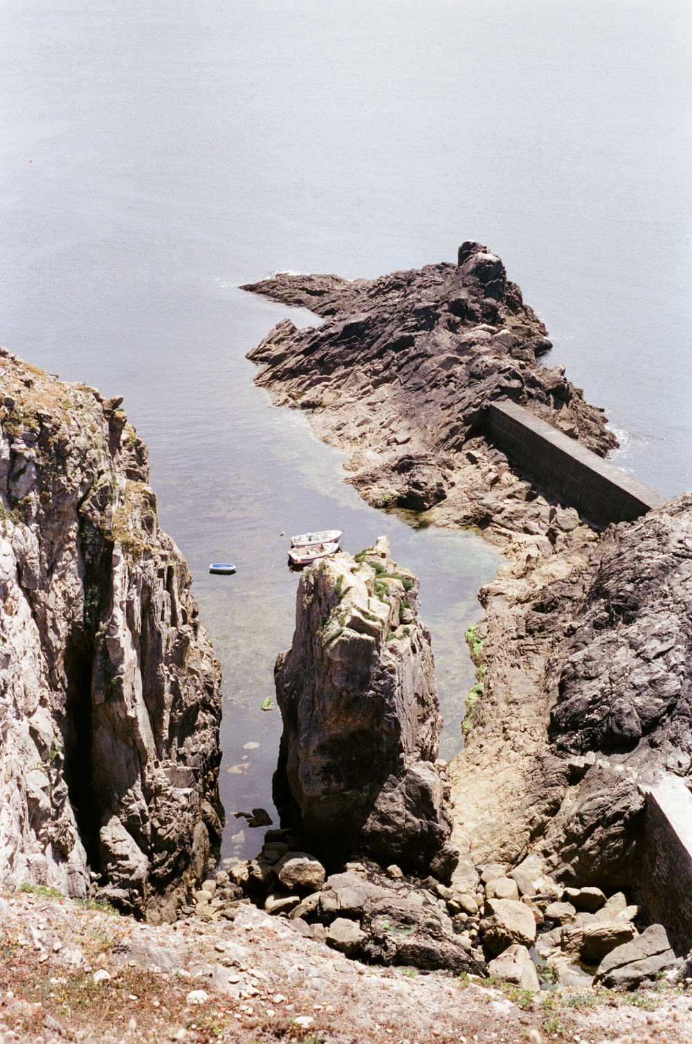 a rocky cliff with a boat in the water