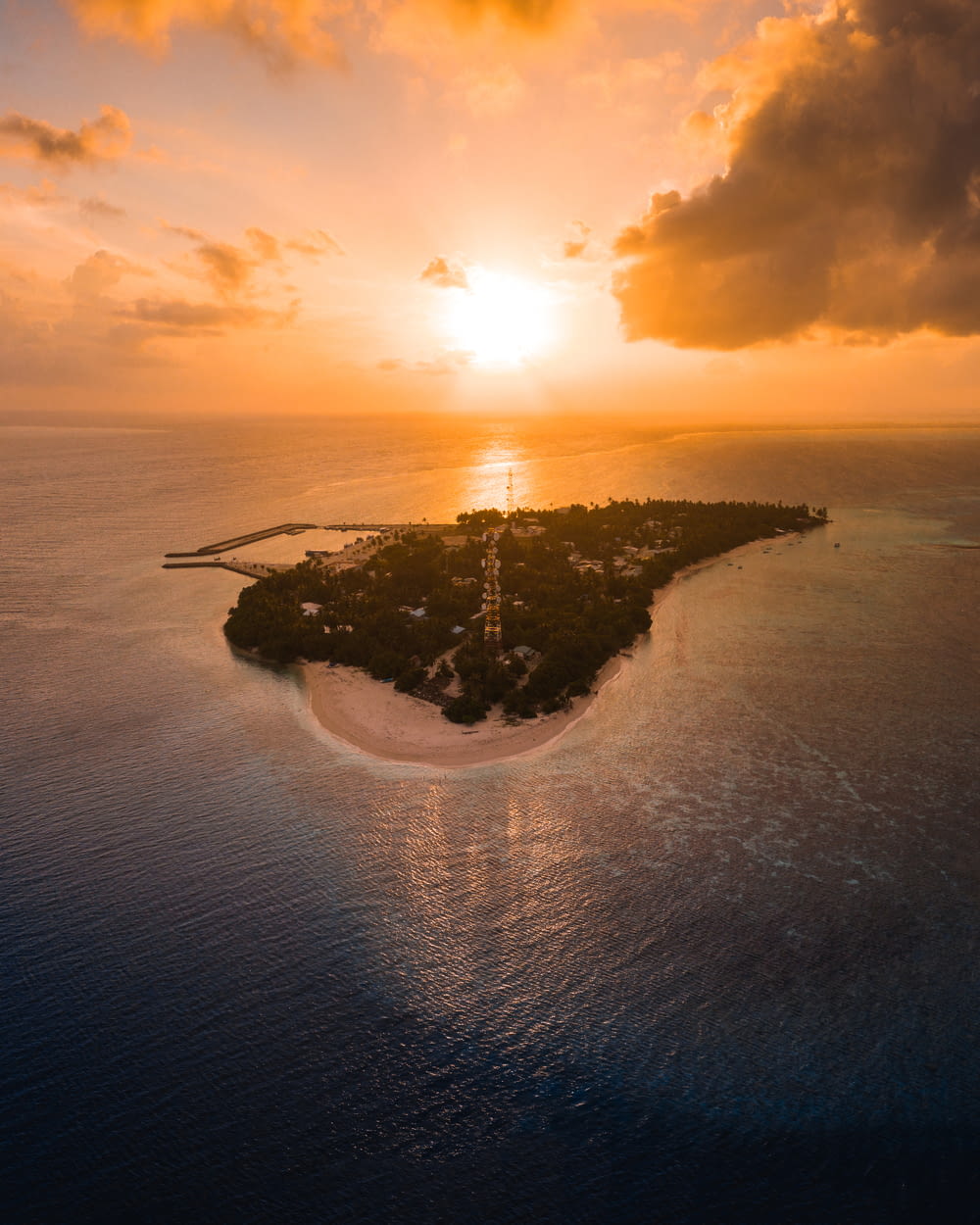 uma ilha no meio do oceano com o pôr do sol