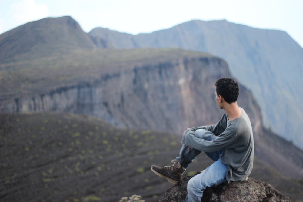 a man sitting on a rock overlooking a valley