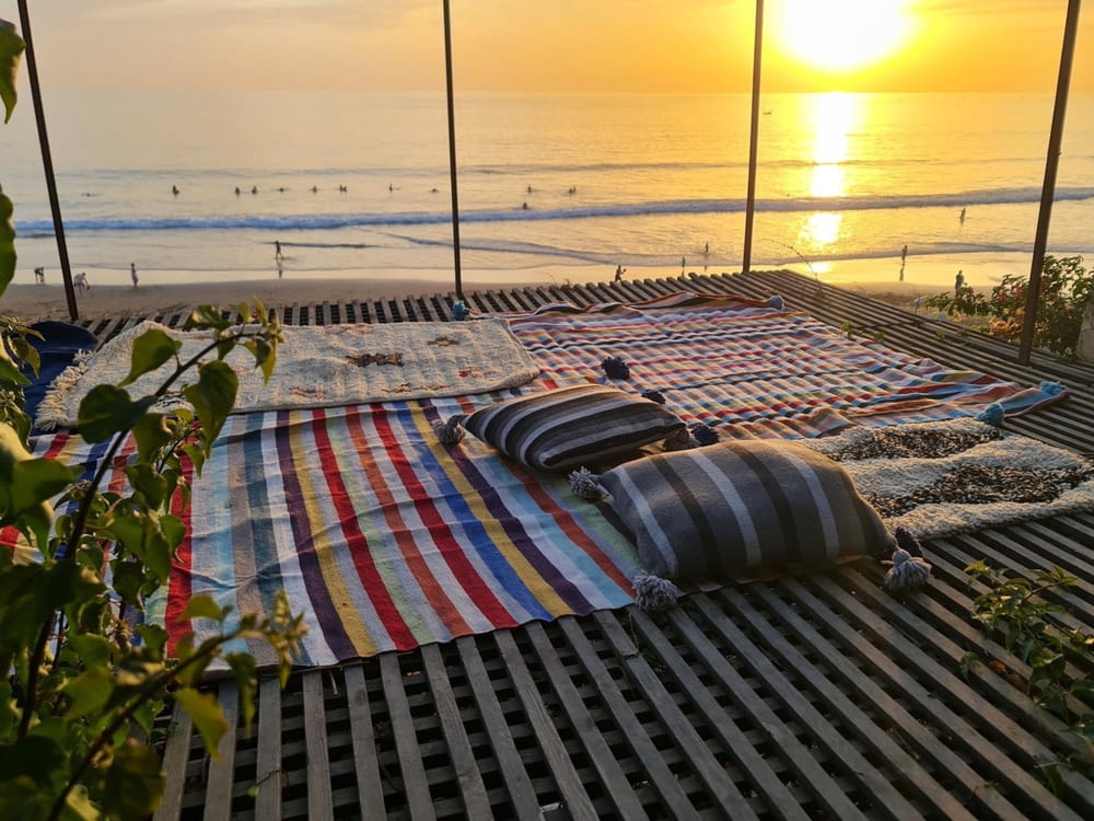 a deck with a blanket and a beach in the background