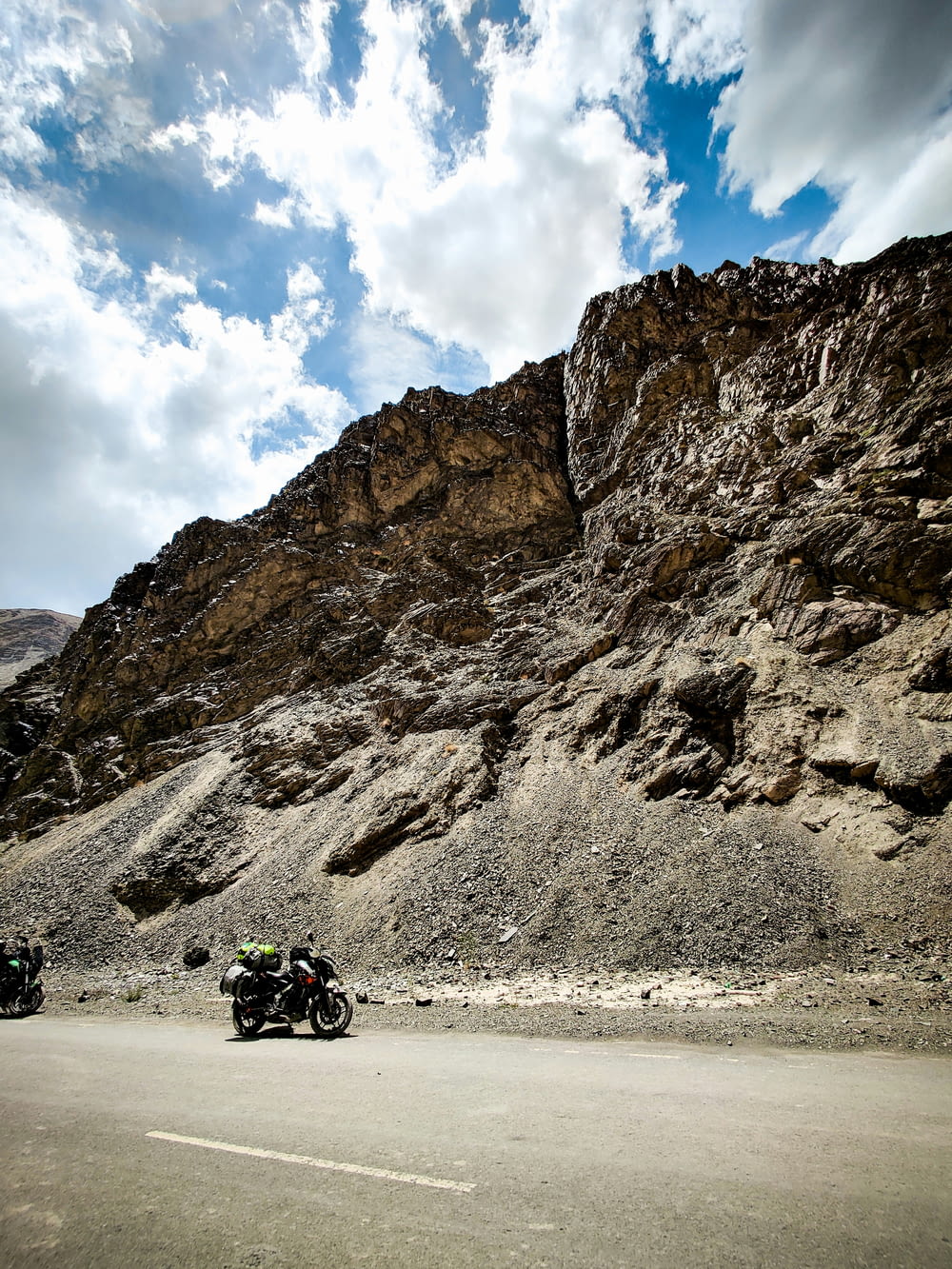 a group of motorcycles parked on a road next to a large rock