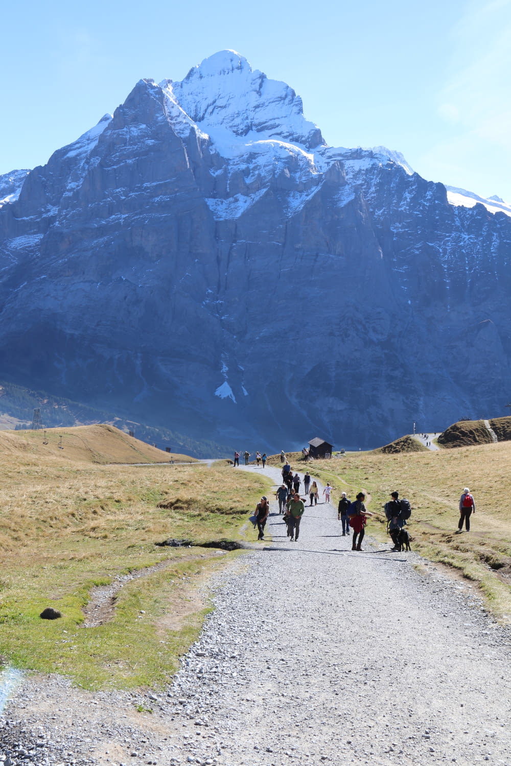 un groupe de personnes marchant sur un chemin de terre devant une grande montagne