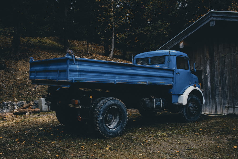 a blue truck parked in front of a wooden building